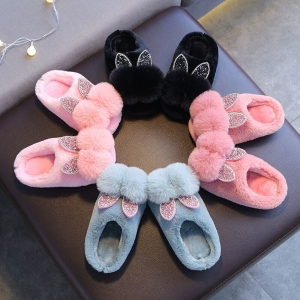 Pantofola con doppio pom-pom per bambina su una sedia, diversi colori