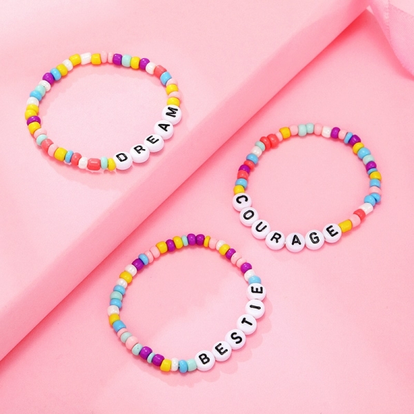 Bracciale di perline con lettere colorate per una bambina su sfondo rosa