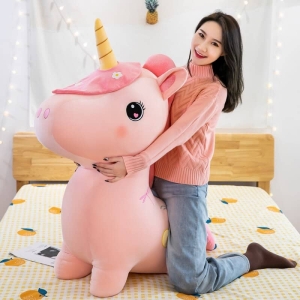 Grande peluche di unicorno per bambina su un letto con una ragazza in una casa