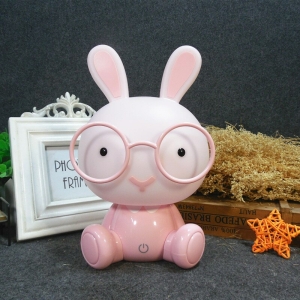 Luce notturna a LED rosa da bambina a forma di coniglietto con lunetta su un tavolo con cornice bianca