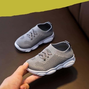 Un paio di scarpe da ginnastica grigie antiscivolo, tenute in mano da un adulto