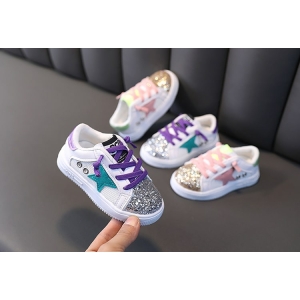 4 paia di scarpe da ginnastica glitterate da bambina su un divano nero