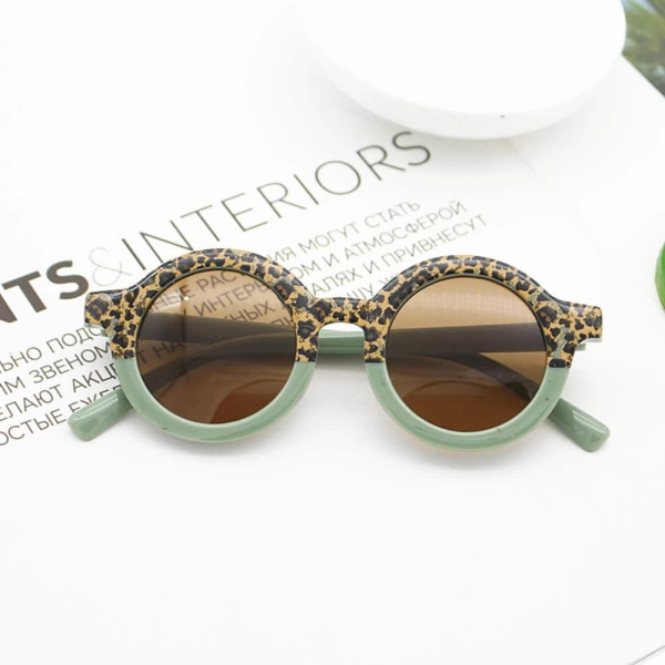 Un paio di occhiali da sole con la montatura per metà verde e per l'altra metà con un motivo animale, incastonati in una pagina di rivista