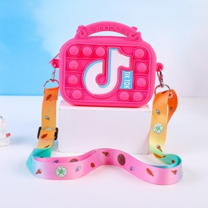 Una piccola borsa rosa scuro con la scritta tiktok su un tavolo bianco. La borsa ha anche delle piccole palline pop it e una tracolla colorata