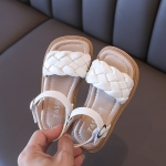 Sandali estivi in pelle intrecciata per una bambina su una sedia