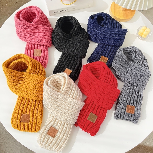 sette sciarpe annodate e disposte su un tavolo rotondo bianco, i colori sono rosa, nero, blu scuro, giallo, bianco, rosso e grigio su un tavolo bianco