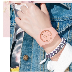 Una giovane ragazza, di cui si vede solo il busto, indossa una giacca di jeans e un semplice orologio in silicone rosa con braccialetto