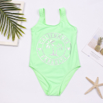 appoggiato accanto a una foglia di palma, una stella marina e una rivista, un costume da bagno verde fluorescente con una scritta argentata sul davanti