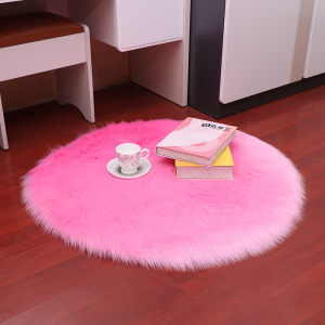 Tappeto rotondo in pelliccia sintetica a pelo lungo di colore rosa con una tazza e due libri sopra