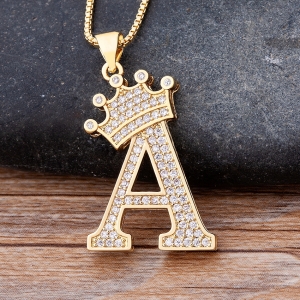 Una collana con l'iniziale del nome di una bambina con la lettera A e una corona sopra la lettera. La collana a maglie è color oro con la lettera a e strass,