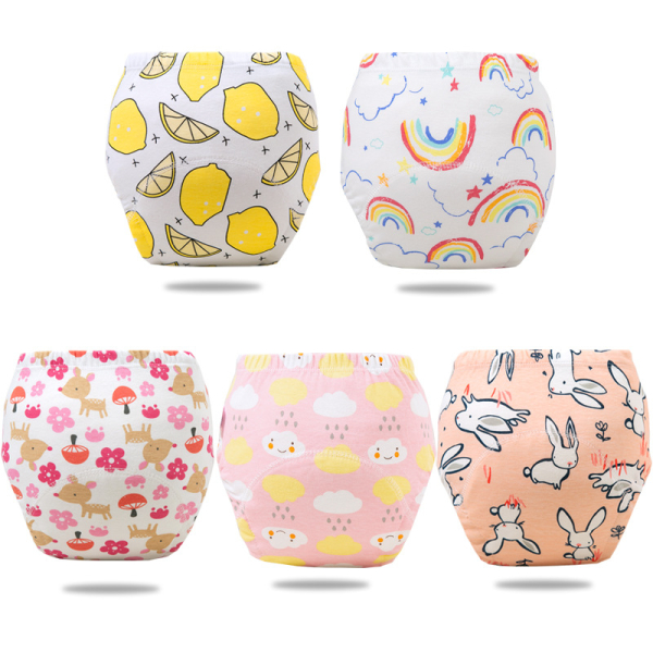Su uno sfondo bianco, 5 pantaloni da allenamento impermeabili per bambine: uno bianco con motivi di limoni, uno bianco con motivi di arcobaleno, uno bianco con cervi beige e fiori rosa, uno rosa con nuvole sorridenti gialle e bianche e gocce di pioggia e uno pesca con conigli bianchi