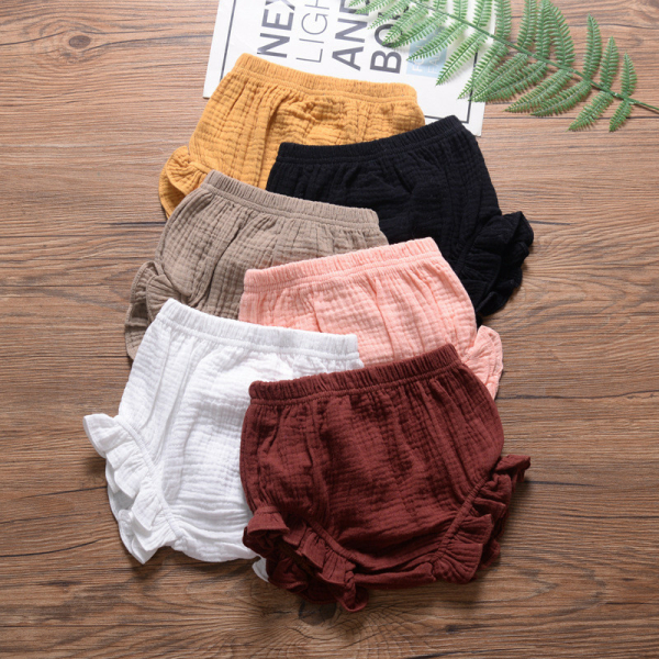 86512-imivq6.jpg Su uno sfondo di parquet con decorazioni di foglie verdi, set di tutine per neonati in mussola goffrata e soffiata, gialle, nere, beige, rosa, bianche e bordeaux