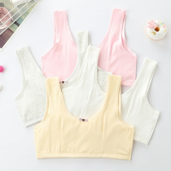 4 reggiseni nei colori rosa, grigio, bianco e giallo, posati in piano