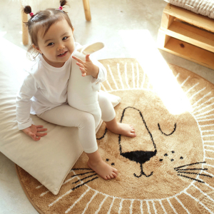Tappeto per la camera dei bambini in stile nordico a forma di leone per una bambina con una bambina sul tappeto