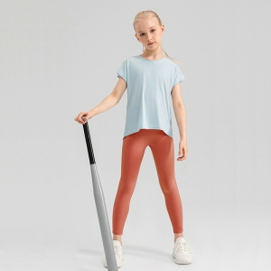 Giovane ragazza bionda in abbigliamento sportivo a piedi con una mazza da baseball in mano