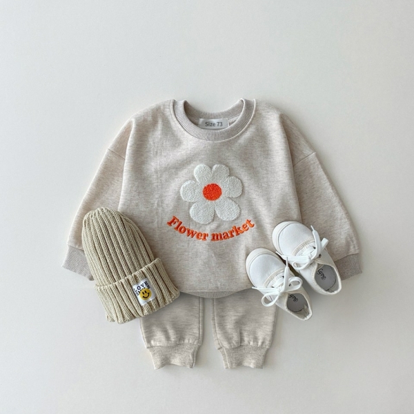 Felpa beige e tuta da jogging con fiore sul davanti, con un paio di scarpe da ginnastica e un cappello