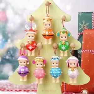 7 statuette Sonny Angel appese a un albero di Natale beige, con uno sfondo decorato in stile natalizio