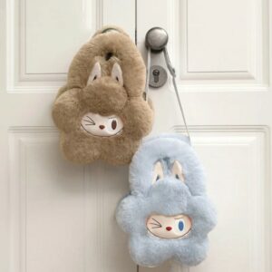 due piccole borsette morbide a forma di fiore, con faccina di Labubu che fa l’occhiolino e grandi orecchie da coniglio. Una azzurra e una marrone chiaro appese a una maniglia