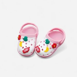 Mini zoccoli stile Crocs colorati, rosa e bianchi, con piccoli charms colorati sopra, su sfondo neutro
