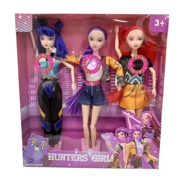 Trois poupées K-pop chantantes dans une boîte rose, avec cheveux colorés, vêtements stylés et bouton lumineux interactif sur la poitrine